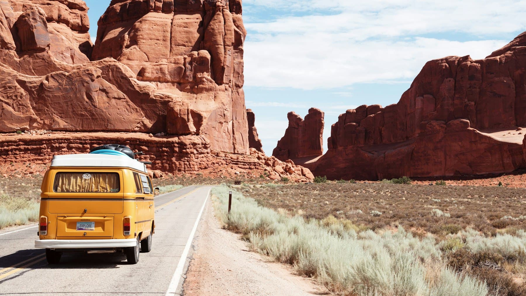 A camper van on an empty road through red-rock canyon country